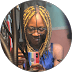 Smiling person with yellow braids and glasses taking a selfie with a colorful phone case.